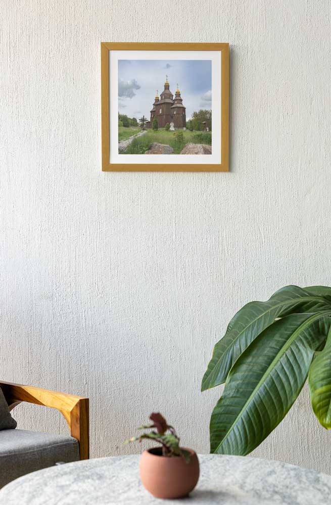 Framed photograph of a church on a wall in a room with a plant and chair. calendar photo frame, calendar frames